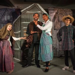 4 villagers pose in front of cutouts of houses