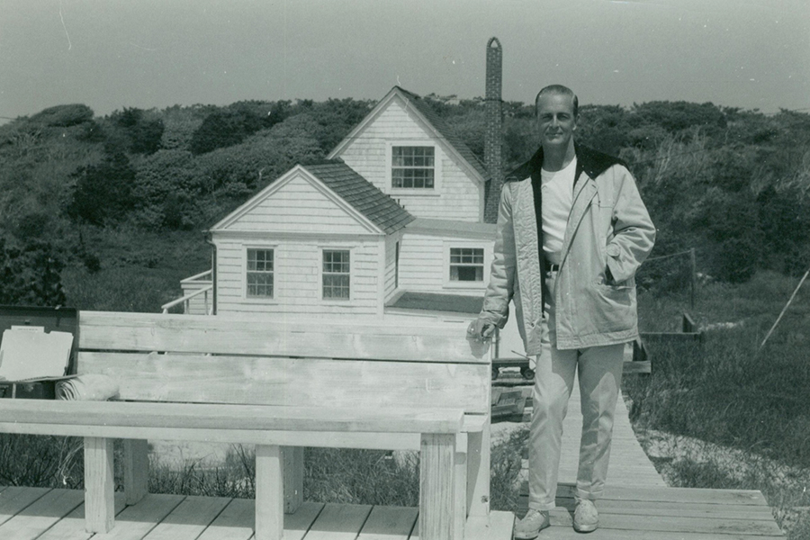 Frank Carrington standing next to a bench. His Fire Island home is in the background