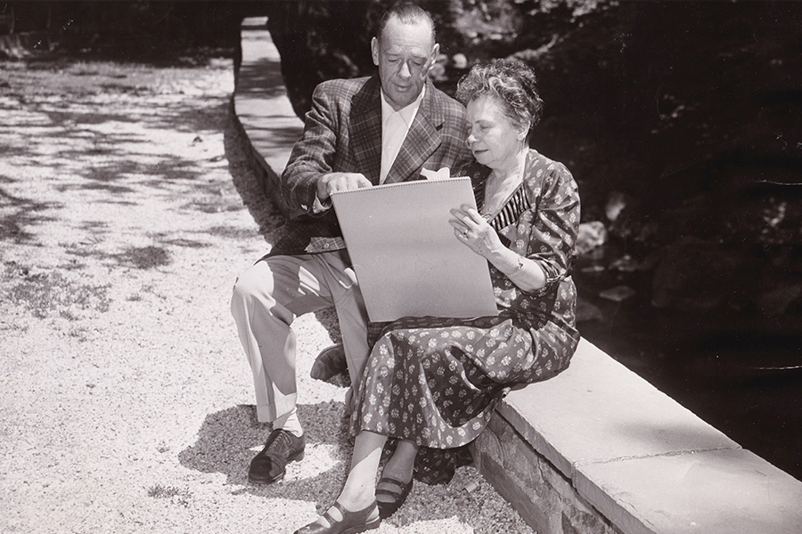 Frank Carrington and Antoinette Scudder sitting brookside looking at a drawing